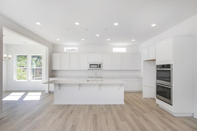 3044 Fernwood Ln, Columbia, TN 38401 - kitchen featuring appliances with stainless steel finishes, white cabinetry, light countertops, a center island with sink, and light wood-type flooring