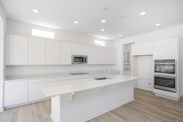 3044 Fernwood Ln, Columbia, TN 38401 - kitchen with stainless steel appliances, white cabinets, a center island with sink, a breakfast bar, and light wood-style flooring