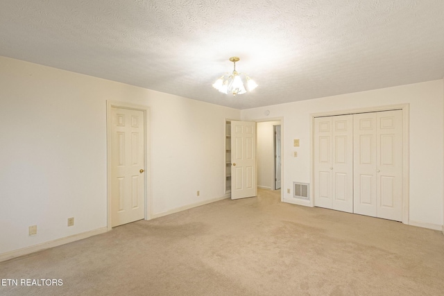 182 Whippoorwill Dr, Oak Ridge, TN 37830 - unfurnished bedroom featuring a chandelier, light colored carpet, a textured ceiling, and a closet