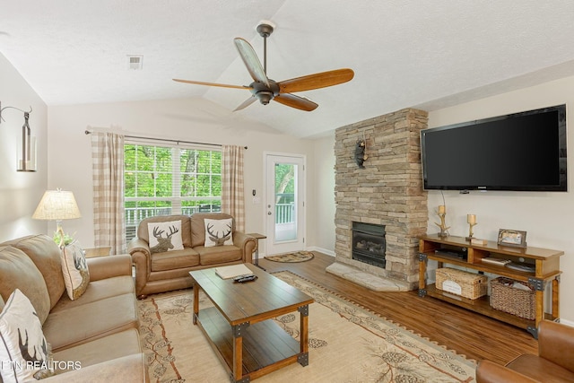 2032 Slippery Rock Cir, Sevierville, TN 37862 - living room with light wood-type flooring, a ceiling fan, lofted ceiling, a stone fireplace, and a textured ceiling