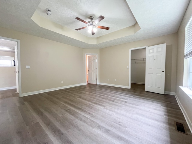1564 Laurel Ledge Dr, La Vergne, TN 37086 - unfurnished bedroom featuring a tray ceiling, a textured ceiling, wood finished floors, a walk in closet, and a ceiling fan
