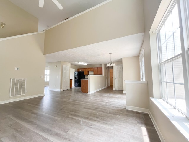 1564 Laurel Ledge Dr, La Vergne, TN 37086 - unfurnished living room with a high ceiling, a chandelier, ceiling fan, light wood finished floors, and crown molding