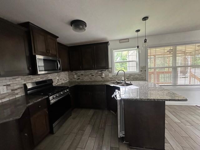 1248 Rich Ellen Dr, Palmyra, TN 37142 - kitchen with appliances with stainless steel finishes, light wood-style flooring, light stone counters, a peninsula, and tasteful backsplash