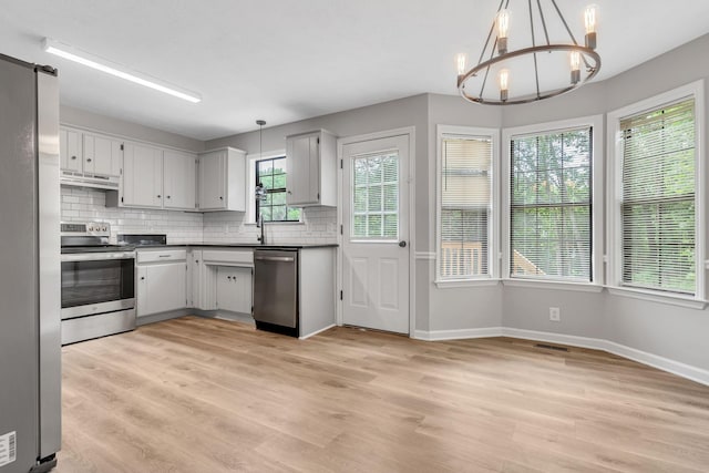 905 Septo Ct, Antioch, TN 37013 - kitchen with stainless steel appliances, under cabinet range hood, a chandelier, backsplash, and dark countertops