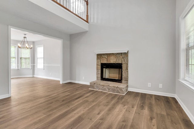905 Septo Ct, Antioch, TN 37013 - unfurnished living room with a chandelier, wood finished floors, healthy amount of natural light, a stone fireplace, and a towering ceiling