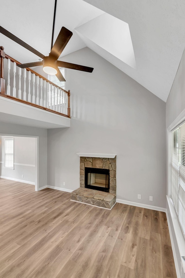 905 Septo Ct, Antioch, TN 37013 - unfurnished living room with high vaulted ceiling, a ceiling fan, a fireplace, wood finished floors, and a skylight