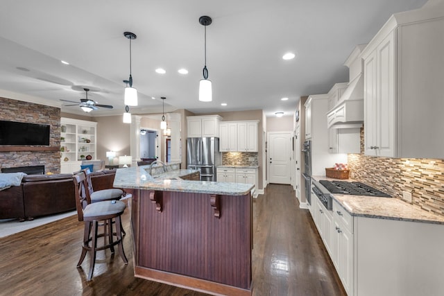 1794 Balvenie Ct, Brentwood, TN 37027 - kitchen with appliances with stainless steel finishes, open floor plan, a stone fireplace, white cabinetry, and recessed lighting