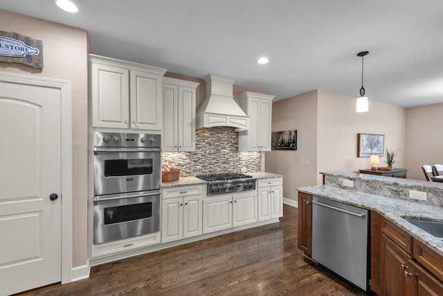1794 Balvenie Ct, Brentwood, TN 37027 - kitchen featuring appliances with stainless steel finishes, premium range hood, white cabinetry, decorative backsplash, and dark wood-style flooring