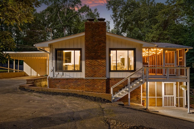 5920 Dogwood Dr, Harrison, TN 37341 - view of front of house featuring asphalt driveway, a chimney, a carport, stairway, and a sunroom