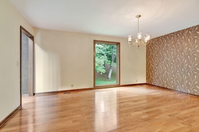 5122 Prince Phillip Cv, Brentwood, TN 37027 - unfurnished room featuring wallpapered walls, wood finished floors, a chandelier, and an accent wall