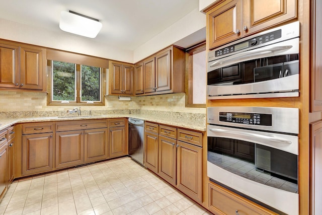5122 Prince Phillip Cv, Brentwood, TN 37027 - kitchen featuring appliances with stainless steel finishes, brown cabinetry, decorative backsplash, and light stone counters