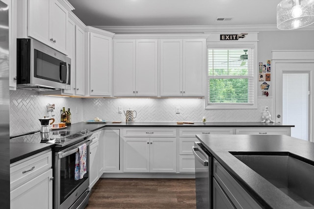 5086 Oop Rd, Chattanooga, TN 37416 - kitchen with appliances with stainless steel finishes, dark countertops, white cabinets, dark wood-style floors, and ornamental molding