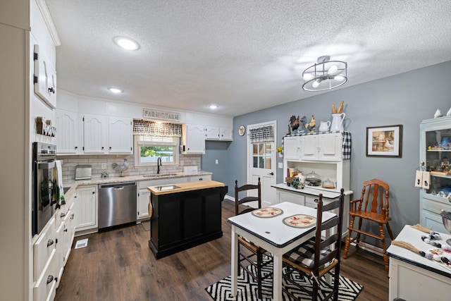 106 Mcfarlin Rd, Murfreesboro, TN 37130 - kitchen with appliances with stainless steel finishes, tasteful backsplash, dark wood-type flooring, white cabinetry, and a textured ceiling