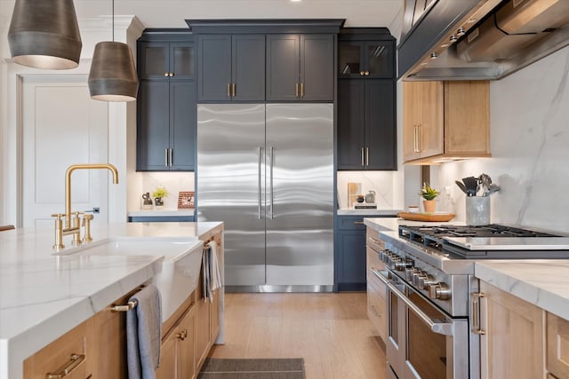 2996 S Rutland Rd, Mount Juliet, TN 37122 - kitchen featuring high quality appliances, exhaust hood, light wood-style floors, light stone countertops, and glass insert cabinets