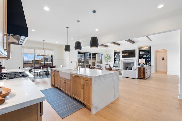 2996 S Rutland Rd, Mount Juliet, TN 37122 - kitchen with light wood finished floors, arched walkways, beamed ceiling, light stone countertops, and a fireplace