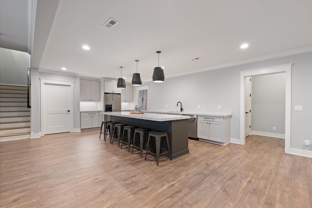 2996 S Rutland Rd, Mount Juliet, TN 37122 - kitchen featuring stainless steel appliances, a kitchen island, a kitchen bar, crown molding, and light wood-style flooring