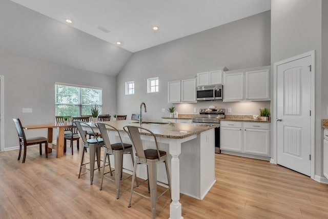 272 Thorpe Dr, Spring Hill, TN 37174 - kitchen with stainless steel appliances, high vaulted ceiling, an island with sink, a kitchen bar, and light stone counters