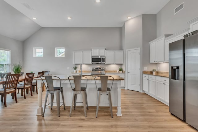 272 Thorpe Dr, Spring Hill, TN 37174 - kitchen featuring stainless steel appliances, high vaulted ceiling, light stone counters, a breakfast bar area, and white cabinetry