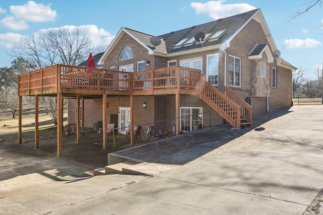 311 Downs Rd, Cumberland City, TN 37050 - rear view of property featuring a deck, concrete driveway, brick siding, and stairs