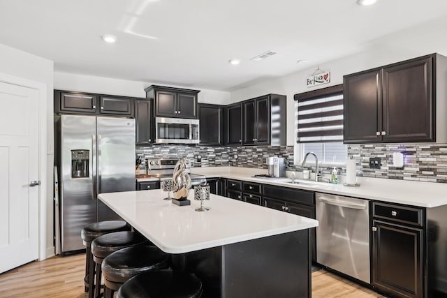 2617 Thornton Grove Blvd, Nashville, TN 37207 - kitchen with appliances with stainless steel finishes, a center island, a kitchen breakfast bar, backsplash, and light wood-type flooring