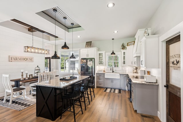 2427 Green Valley Rd, Lafayette, TN 37083 - kitchen featuring stainless steel fridge with ice dispenser, wood finished floors, a breakfast bar area, light stone counters, and recessed lighting