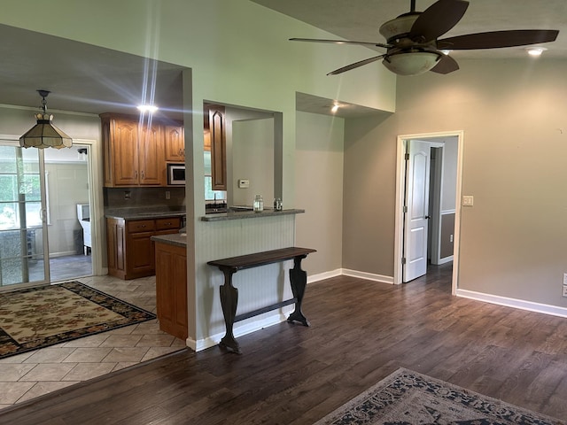 1775 Old Beech Creek Rd, Waynesboro, TN 38485 - kitchen featuring dark countertops, a towering ceiling, a ceiling fan, dark wood-style flooring, and stainless steel microwave