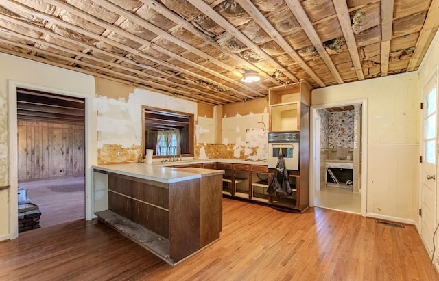 867 Lexington Hwy, Loretto, TN 38469 - kitchen featuring open shelves, white oven, a peninsula, light wood-type flooring, and wainscoting