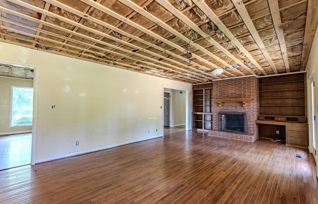 867 Lexington Hwy, Loretto, TN 38469 - unfurnished living room with wood-type flooring, a brick fireplace, and built in shelves