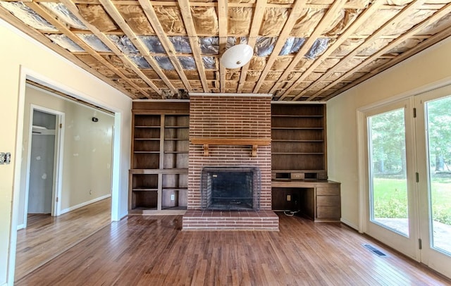 867 Lexington Hwy, Loretto, TN 38469 - unfurnished living room with built in shelves, hardwood / wood-style flooring, and a brick fireplace