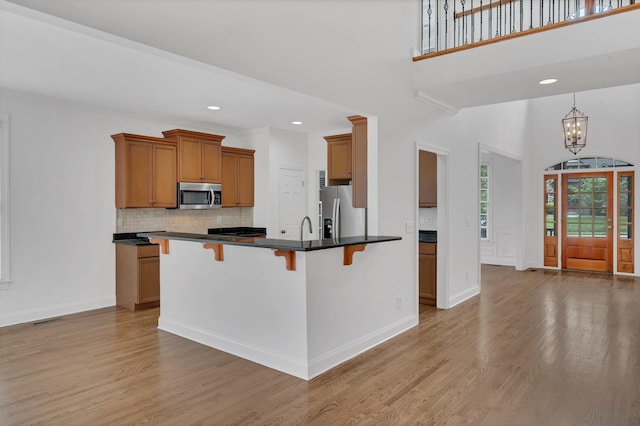 7157 Chessington Dr, Fairview, TN 37062 - kitchen with stainless steel appliances, light wood-style floors, a breakfast bar, dark countertops, and backsplash