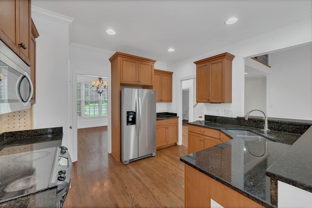 7157 Chessington Dr, Fairview, TN 37062 - kitchen with appliances with stainless steel finishes, light wood finished floors, a chandelier, ornamental molding, and dark stone counters