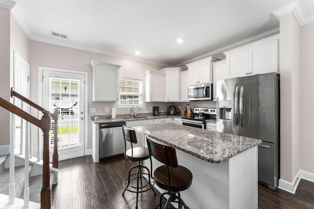 4316 Summercrest Blvd Unit 104, Antioch, TN 37013 - kitchen with appliances with stainless steel finishes, dark wood-type flooring, a kitchen island, crown molding, and a breakfast bar area
