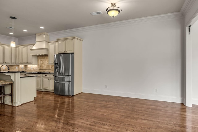 1353 Eliot Rd, Franklin, TN 37064 - kitchen with stainless steel appliances, custom range hood, cream cabinets, dark countertops, and a breakfast bar