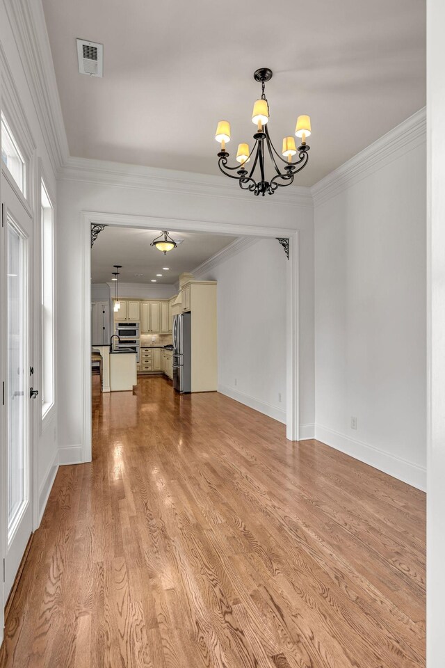 1353 Eliot Rd, Franklin, TN 37064 - unfurnished living room with a chandelier, crown molding, and light wood-style flooring
