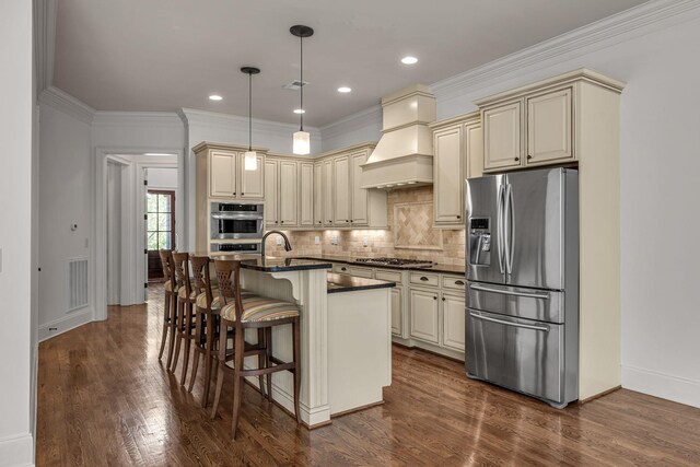1353 Eliot Rd, Franklin, TN 37064 - kitchen with stainless steel appliances, cream cabinets, dark countertops, premium range hood, and ornamental molding