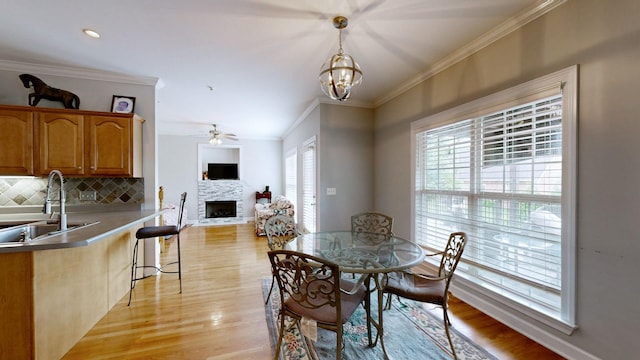 5142 Reagan Dr, Murfreesboro, TN 37129 - dining area with a fireplace, crown molding, ceiling fan, light wood finished floors, and a chandelier