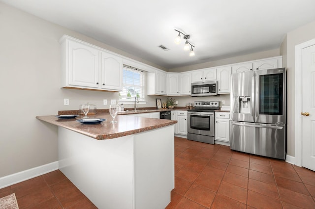 5241 Ticonderoga Ave, Murfreesboro, TN 37129 - kitchen featuring appliances with stainless steel finishes, a peninsula, dark tile patterned flooring, white cabinets, and a breakfast bar area