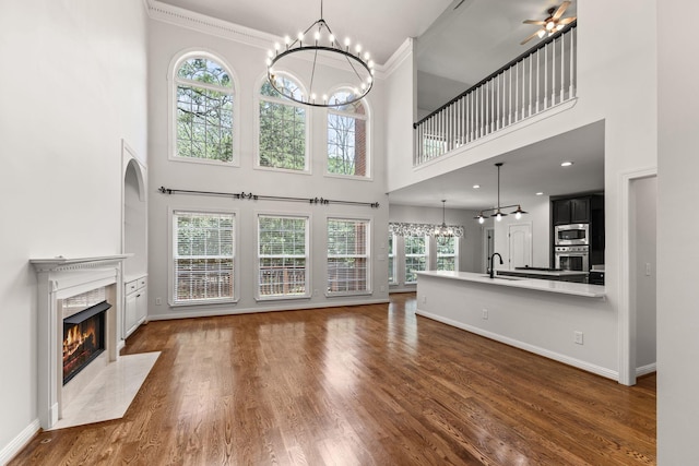 630 Black Horse Pkwy, Franklin, TN 37069 - unfurnished living room with a chandelier, a fireplace, a high ceiling, wood finished floors, and ornamental molding