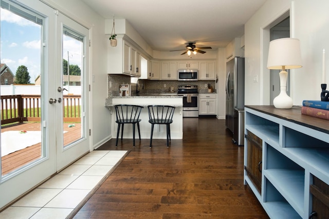 280 Ballygar Ct, Clarksville, TN 37043 - kitchen featuring appliances with stainless steel finishes, wood-type flooring, white cabinets, a peninsula, and healthy amount of natural light