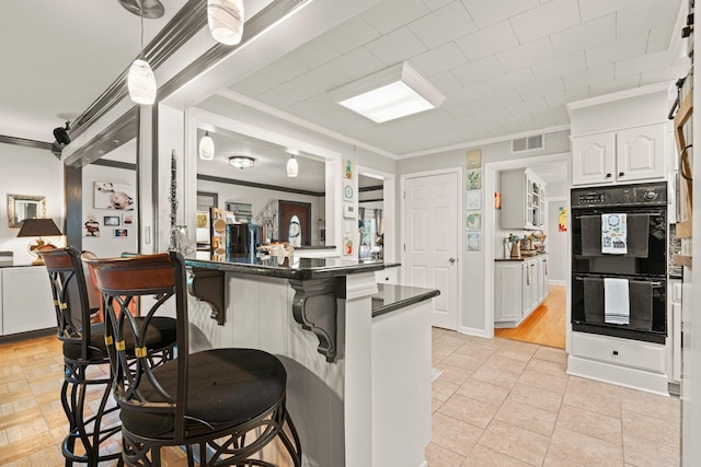 605 Jackson Ave, Carthage, TN 37030 - kitchen with dark countertops, a breakfast bar area, ornamental molding, white cabinetry, and a peninsula