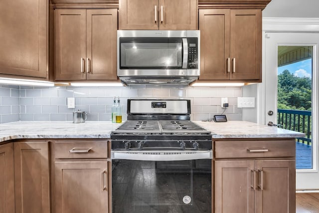 267 Alonzo Pl, Cunningham, TN 37052 - kitchen with gas range oven, stainless steel microwave, decorative backsplash, light stone counters, and wood finished floors