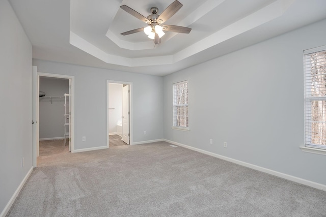 3044 Stone Bridge Rd, Antioch, TN 37013 - unfurnished bedroom featuring a tray ceiling, carpet floors, a walk in closet, and multiple windows