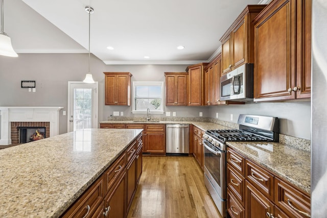 8005 Ragusa Cir, Spring Hill, TN 37174 - kitchen featuring stainless steel appliances, crown molding, light wood finished floors, light stone counters, and brown cabinetry