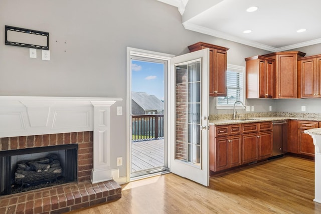 8005 Ragusa Cir, Spring Hill, TN 37174 - kitchen featuring stainless steel dishwasher, light wood-type flooring, light stone counters, crown molding, and a brick fireplace