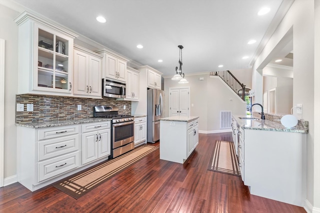 2950 Prince Dr, Clarksville, TN 37043 - kitchen with stainless steel appliances, a kitchen island, dark wood-style floors, glass insert cabinets, and decorative backsplash