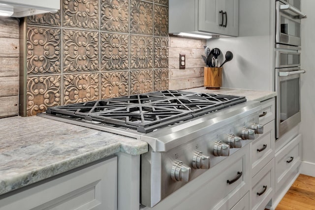 9003 Oden Ct, Brentwood, TN 37027 - kitchen with stainless steel appliances, backsplash, light countertops, white cabinets, and light wood-style floors
