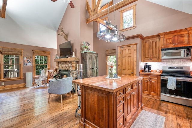 647 Omega Dr, Spring City, TN 37381 - kitchen with appliances with stainless steel finishes, wood counters, high vaulted ceiling, a fireplace, and brown cabinets
