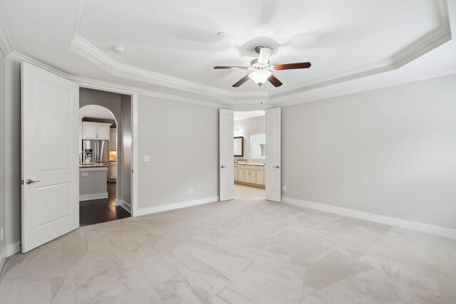 1000 Swanson Ln, Franklin, TN 37064 - unfurnished bedroom featuring a raised ceiling, arched walkways, ornamental molding, light colored carpet, and connected bathroom