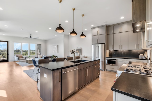 2118 Cliff Dr, Nashville, TN 37218 - kitchen with appliances with stainless steel finishes, dark countertops, light wood-type flooring, backsplash, and an island with sink