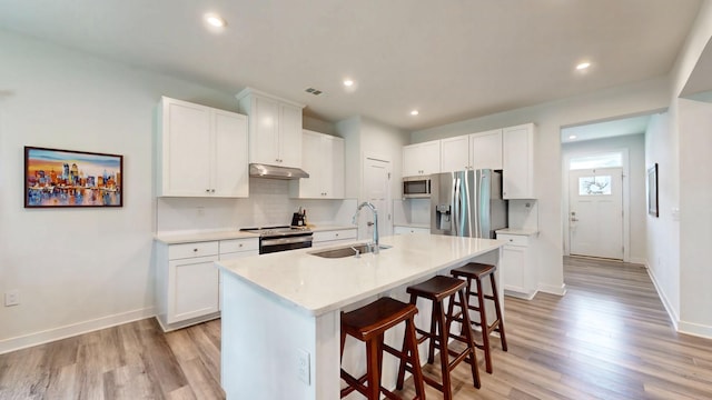 3428 Pepper Glendale Dr, Murfreesboro, TN 37128 - kitchen with stainless steel appliances, under cabinet range hood, a breakfast bar, light wood-style flooring, and tasteful backsplash
